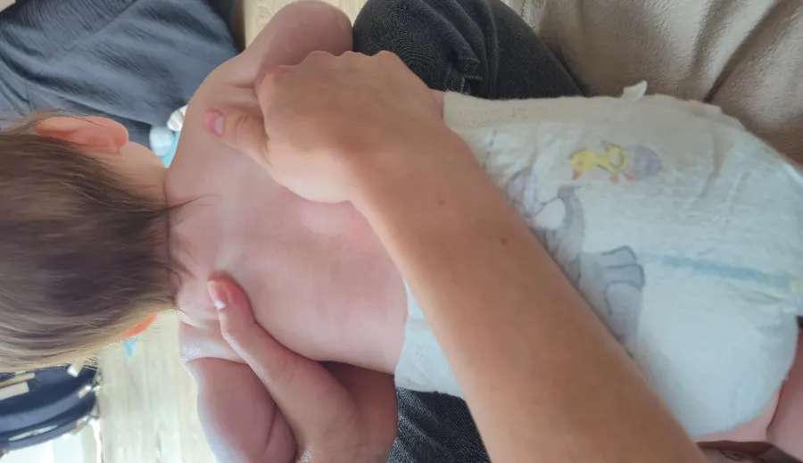 Parent practising a baby massage stroke