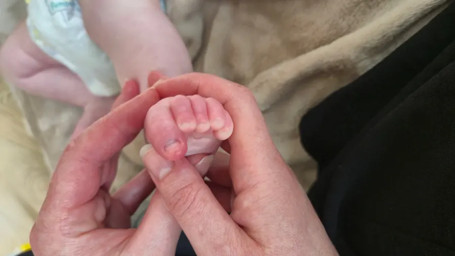 Parent and baby holding hands during baby massage