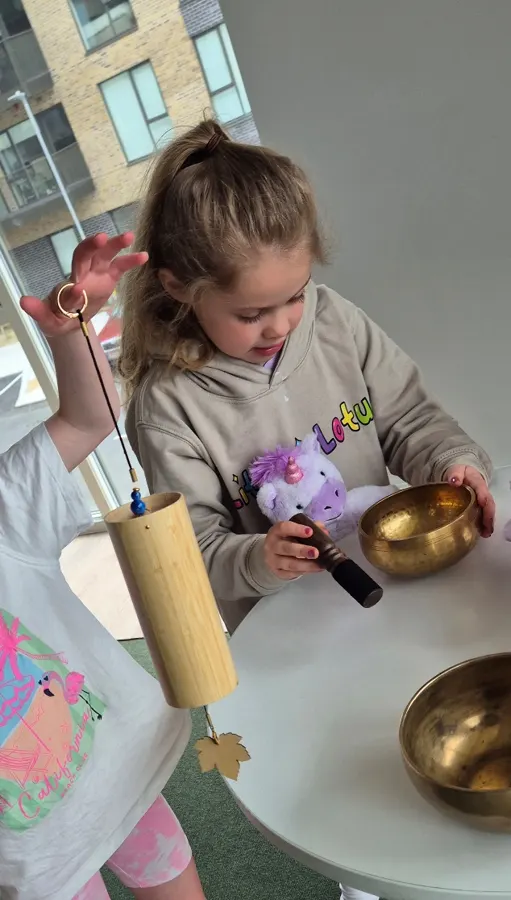 Child playing a singing bowl during a Little Lotus class
